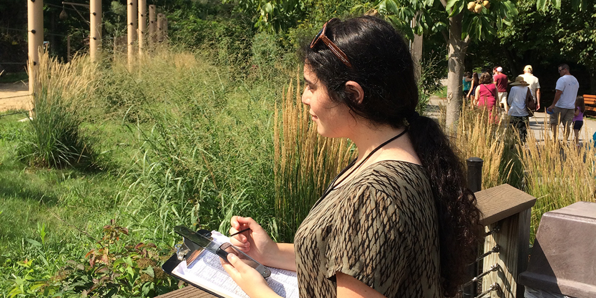 Student Standing on a deck looking into distance with notepad