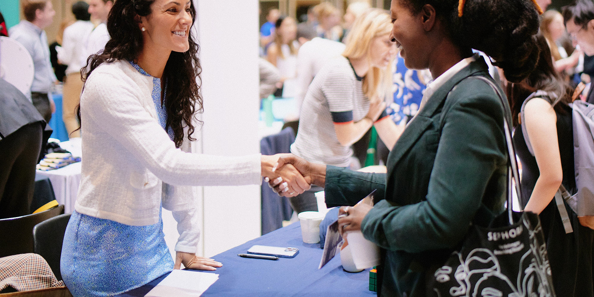 Female recruiter shakes the hand of a Columbia female student at a career fair.