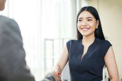 Beautiful Asian businesswoman smiling and shaking hands - Stock image.jpg 