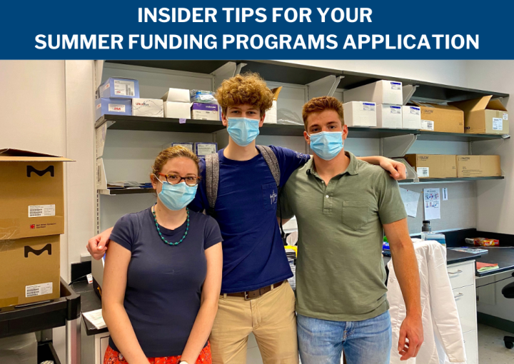 Three people stand in a lab wearing blue masks