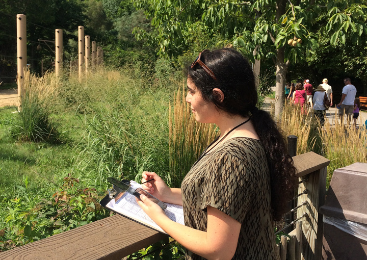 Student Standing on a deck looking into distance with notepad