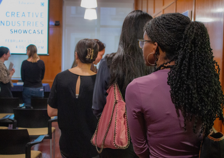 The backs of students in a line to meet with an employer at the Creative Industries Showcase, which is on a sign in the background